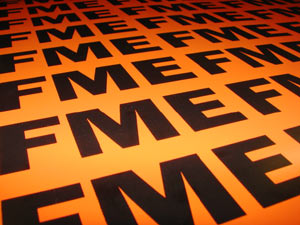 A closeup of a field of black FMEs on an orange background