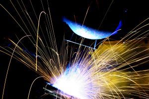 A welder with sparks flying on a dark background
